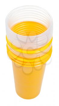 disposable dishes - stack of yellow and transparent plastic glasses isolated on white background