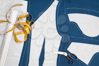 fitter tools and paper model of clothes on blue fabric for dress cutting