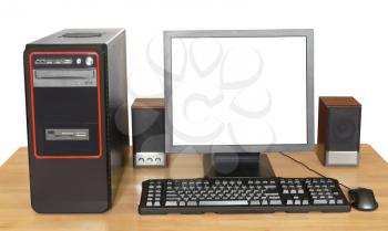 black desktop computer, display with cutout screen, keyboard, mouse, speakers on wooden table isolated on white background