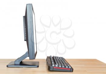 side view of computer display with cut out screen and keyboard on wooden table isolated on white background