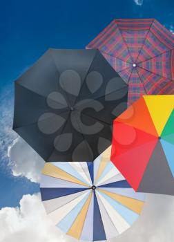 four different open umbrellas with cloudy dark blue sky background