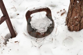 old weight in yard under the snow in winter day