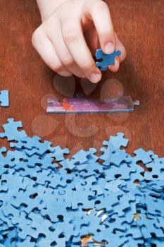 choosing of jigsaw puzzles on wooden table