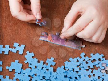 fitting of jigsaw puzzles on wooden table