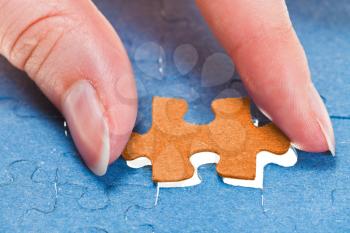 inserting the last orange piece of puzzle in free space in assembled jigsaw puzzles