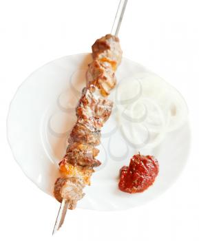 above view of skewer with lamb shish kebab on white plate isolated on white background