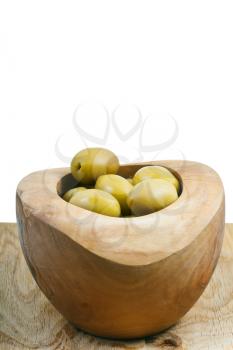 green olives in bowl on wooden plate close up isolated on white background