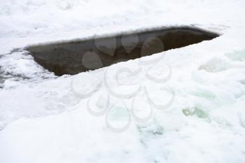 ice-hole with frozen water in pond and ice blocks in winter day