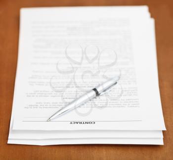 sheets of sales contract and silver pen on wooden table