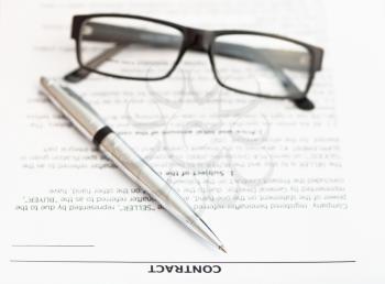 silver pen and eyeglasses on pages of sales contract