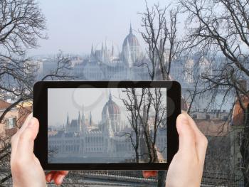 travel concept - tourist taking photo of Hungarian Parliament Building in spring morning on mobile gadget, Hungary