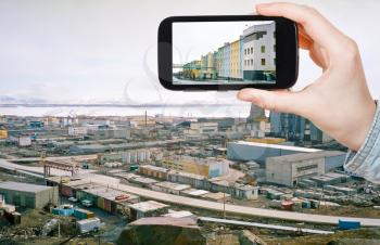 travel concept - tourist taking photo of Anadyr town skyline on mobile gadget in spring, Chukotka, Russia