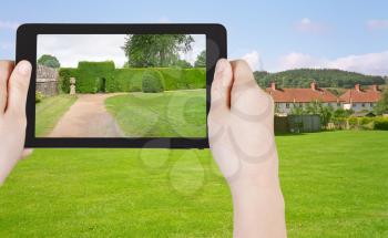travel concept - tourist taking photo of green lawn in South England country on mobile gadget
