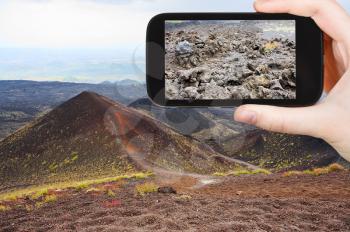 travel concept - tourist taking photo of craters volcano Etna on mobile gadget, Sicily, Italy