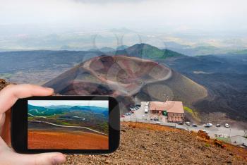 travel concept - tourist taking photo of station Rifugio Sapienza on Etna on mobile gadget, Sicily, Italy