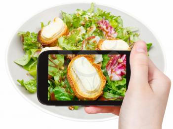photographing food concept - tourist taking photo of green salad with goat cheese on mobile gadget, Italy
