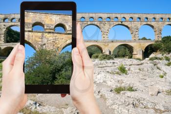 travel concept - tourist taking photo of Pont du Gard - ancient Roman aqueduct on mobile gadget, France