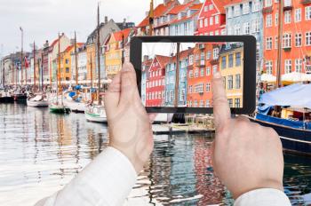 travel concept - tourist taking photo of Nyhavn harbor district in Copenhagen on mobile gadget, Denmark