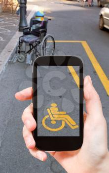 travel concept - tourist taking photo of parking space for disabled people and wheelchair on mobile gadget