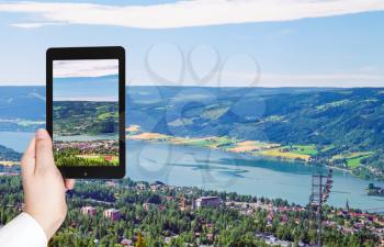 travel concept - tourist taking photo of Lillehammer town in Norway on mobile gadget