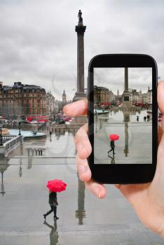travel concept - tourist taking photo of trafalgar square in London on mobile gadget, England