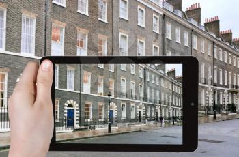 travel concept - tourist taking photo of houses in London in overcast day on mobile gadget, Great Britain