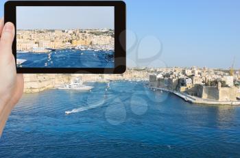 travel concept - tourist taking photo of skyline of Valletta city in summer day, Malta on mobile gadget