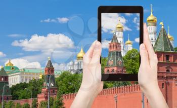 travel concept - tourist taking photo of Wall and Cathedrals of Moscow Kremlin on mobile gadget, Russia