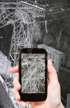 travel concept - tourist taking photo of electric power line of Hoover Dam on mobile gadget, USA