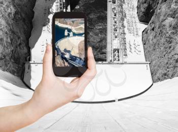 travel concept - tourist shooting photo of above view of of Hoover Dam on mobile gadget, USA