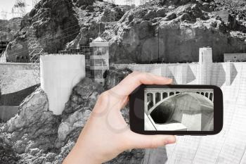 travel concept - tourist shooting photo of Hoover Dam on mobile gadget, USA
