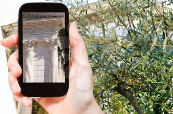 travel concept - tourist taking photo of ancient roman temple Maison Carree, Nimes, Franceon mobile gadget