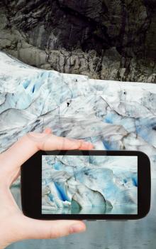 travel concept - tourist taking photo of snow briksdal glacier in Norway on mobile gadget
