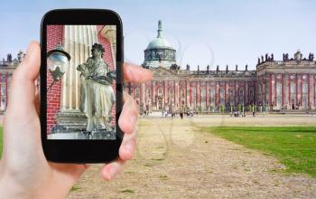 travel concept - tourist taking photo of scupture of New Palace in Sanssouci Royal Park, Potsdam on mobile gadget, Germany