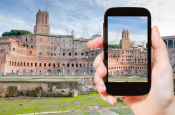 travel concept - tourist taking photo of ancient ruins of roman forum on Capitoline Hill in Rome, Italy on mobile gadget