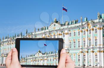 travel concept - tourist taking photo of Russian state flag on Winter Palace, St.Petersburg, Russia on mobile gadget