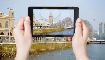 travel concept - tourist taking photo of waterfront in Zurich in winter on mobile gadget, Switherland