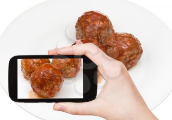 photographing food concept - tourist takes picture of three meatballs under meat sauce on smartphone, Sweden