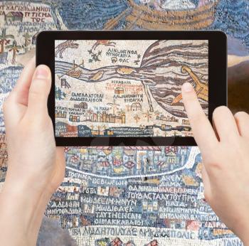 travel concept - tourist takes picture of ancient byzantine map of Holy Land, Madaba on smartphone, Jordan
