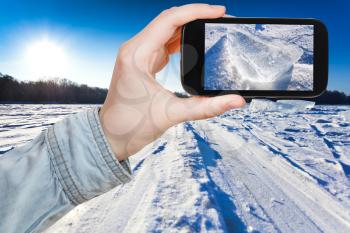 travel concept - tourist takes picture of ski track at snow field in cold winter day on smartphone, Moscow