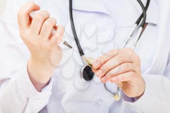 nurse fills syringe from vial close up