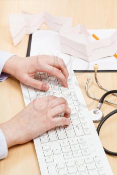 medic works on white PC keyboard close up