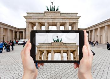 travel concept - tourist takes picture of Brandenburg gate in Belin in cloudy autumn day on Pariser Platz on tablet pc