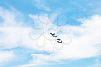 four military fighter airplanes in white clouds in blue sky