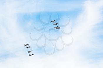 flight of military pursuit aircrafts in white clouds in blue sky