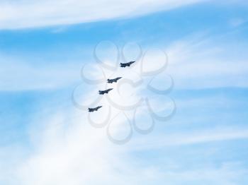 four military fighter planes in cloudy blue sky