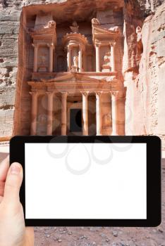 travel concept - tourist photograph temple in ancient town Petra - Treasury Monument, Jordan on tablet pc with cut out screen with blank place for advertising logo