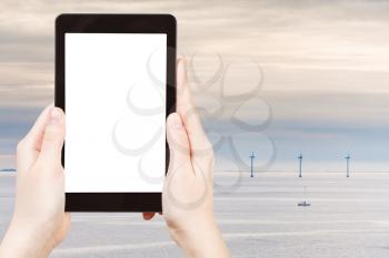 travel concept - tourist photograph Middelgrunden - offshore wind farm near Copenhagen, Denmark at early morning on tablet pc with cut out screen with blank place for advertising logo