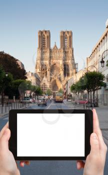 travel concept - tourist photograph gothic catholic Notre Dame Cathedral in Reims, Franceon tablet pc with cut out screen with blank place for advertising logo