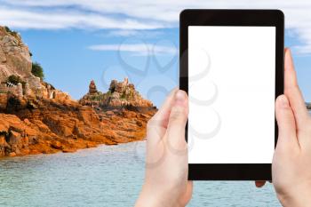 travel concept - tourist photograph coastline of breton island Ile de Brehat in France on tablet pc with cut out screen with blank place for advertising logo
